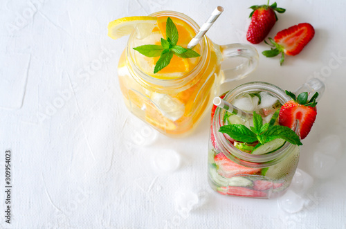 Summer refreshing iced drinks with orange, lemon, cucumber and strawberry on white background