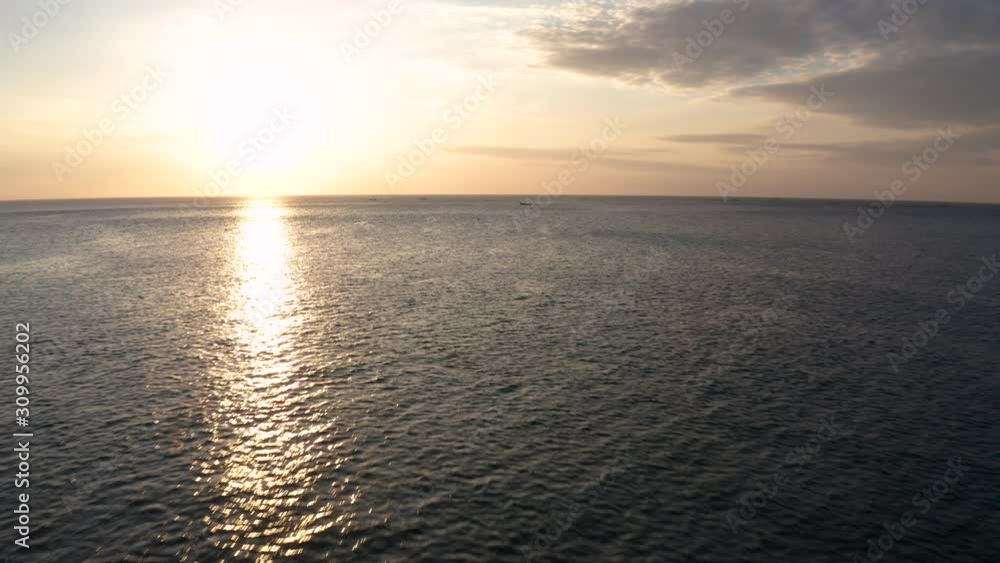 Forwarding drone in middle of Indian ocean to film sunset in golden hour with amazing sunlight reflection with golden red sun, clouds and traditional fisherman sailing boat in background in 4k. Forwarding drone in middle of Indian ocean to film sunset in golden hour with amazing sunlight reflection with golden red sun, clouds and traditional fisherman sailing boat in background in 4k.