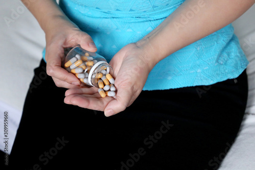 Woman with pills sitting on a bed  female hands with bottle of capsules. Concept of vitamins for beauty  diet pill  contraceptive  medication for stomach or sleeping pill