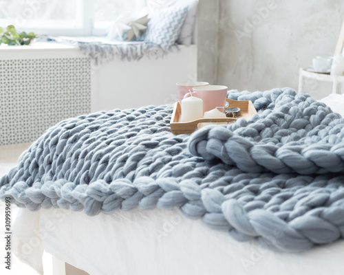 A gray plaid of merino wool lies on the bed. A tray with mugs on a plaid. Cozy interior. photo