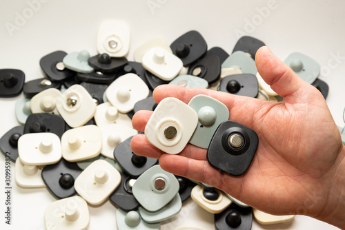 Photos many multi-colored anti-theft sensor on a man’s male hand on a light background