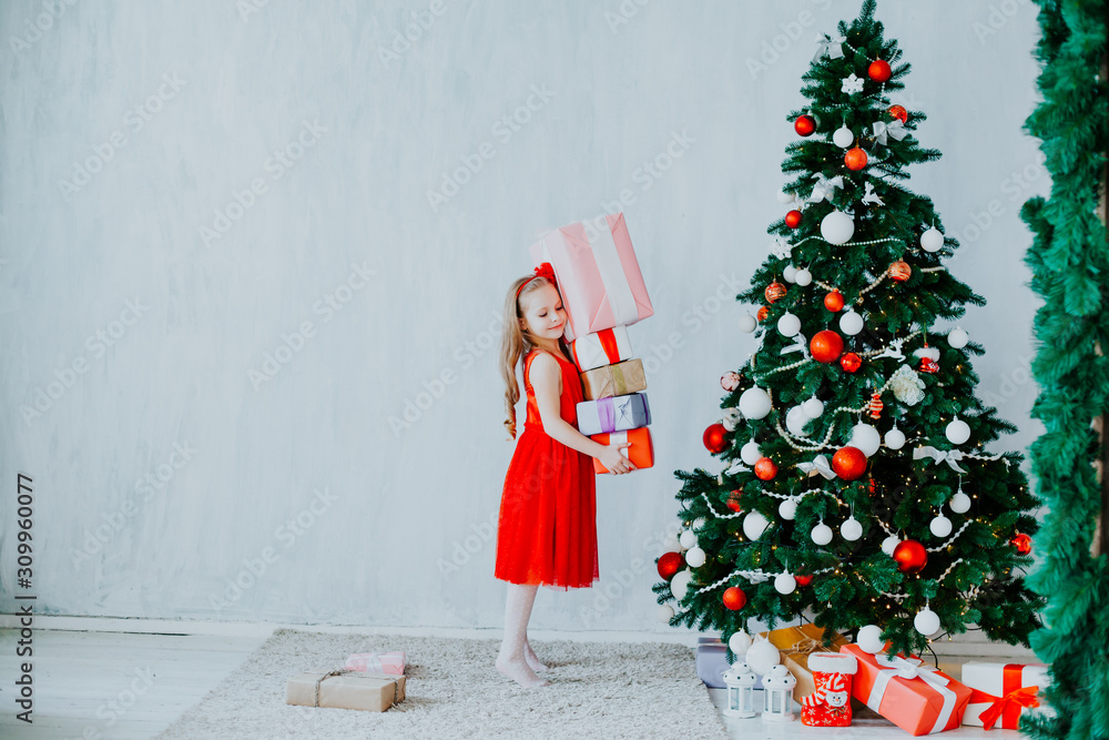 little girl opens Christmas gifts at the Christmas tree new year holiday house little girl opens Christmas gifts at the Christmas tree new year holiday house