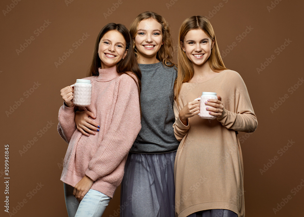 Cute happy girls with cups on brown background