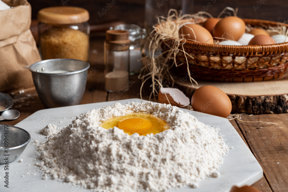 Flour with yolk egg and A lot of eggs put in the basket are placed on the wooden table for cooking something. Flour with yolk egg and A lot of eggs put in the basket are placed on the wooden table for cooking something.