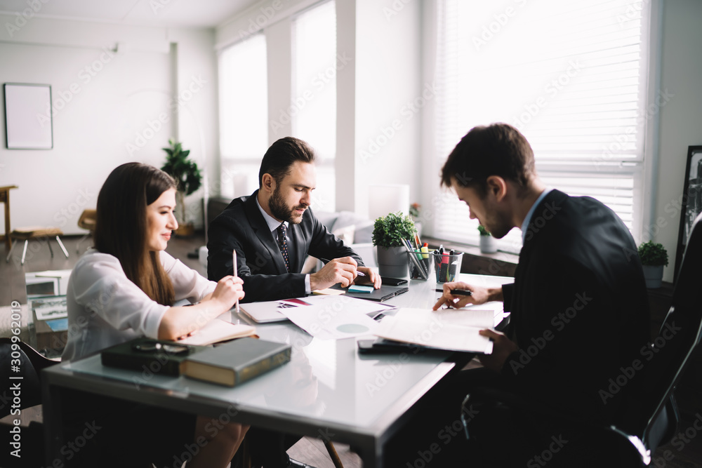 Group of coworkers sitting at table in office Group of coworkers sitting at table in office