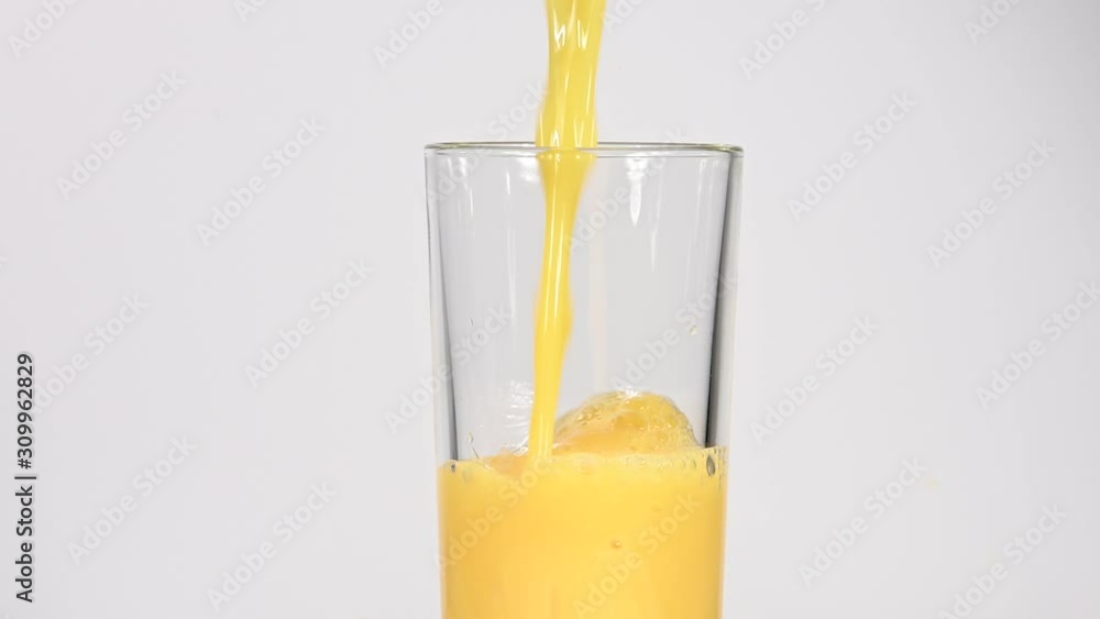 Close up pouring orange juice in glass over white
