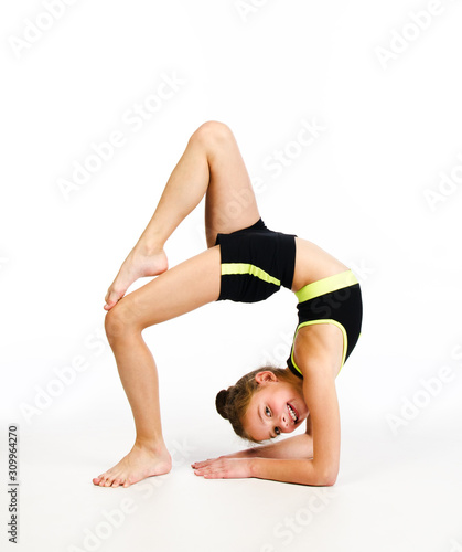 Flexible cute little girl child gymnast doing acrobatic exercise isolated on a white background photo