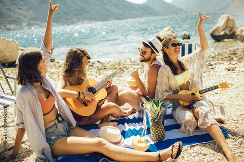 Young friends having fun at the beach on a sunny day. Party time. photo