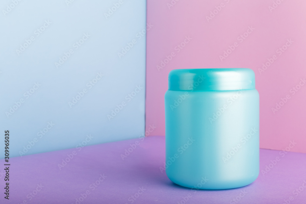 Blue plastic jar with mock up for cosmetic products on color pink background with Copy space. Cosmetic package for hair mask, conditioner shower gel hygiene products, homemade natural cosmetics. Blue plastic jar with mock up for cosmetic products on color pink background with Copy space. Cosmetic package for hair mask, conditioner shower gel hygiene products, homemade natural cosmetics.
