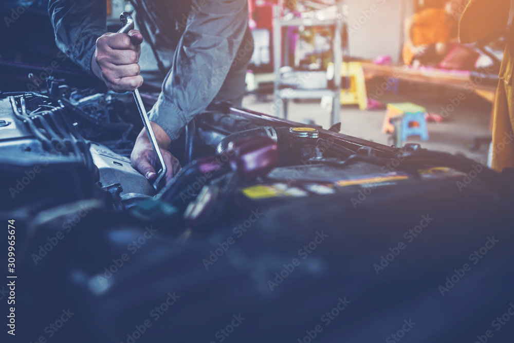 Fototapeta premium technician working on checking and service car in workshop garage; technician repair and maintenance engine of automobile in car service