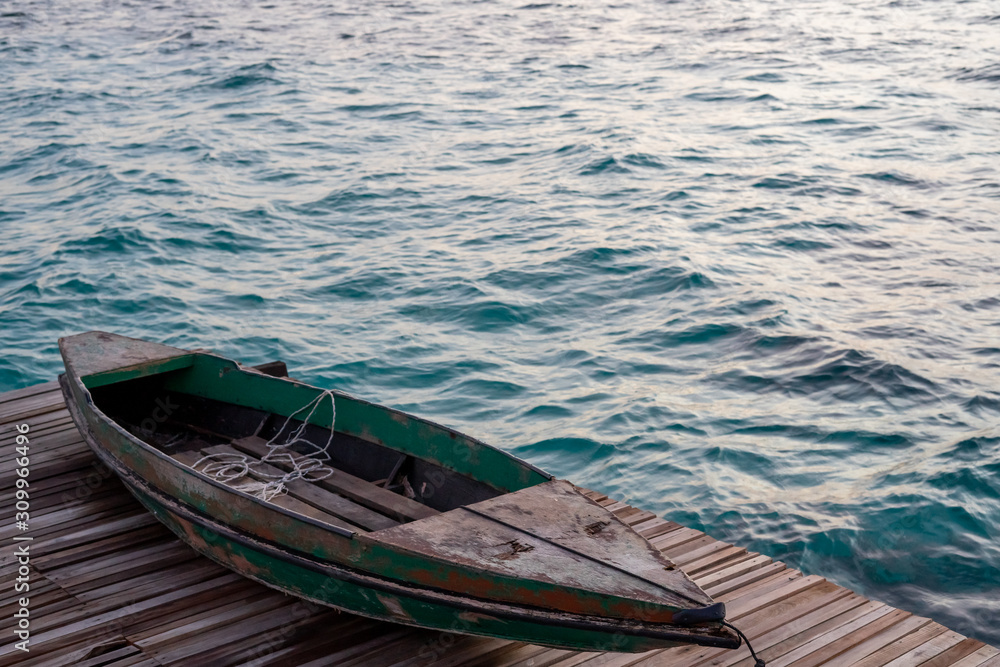 Old wooden boat sitting on the pier overlooking the beautiful Semporna turquoise sea.