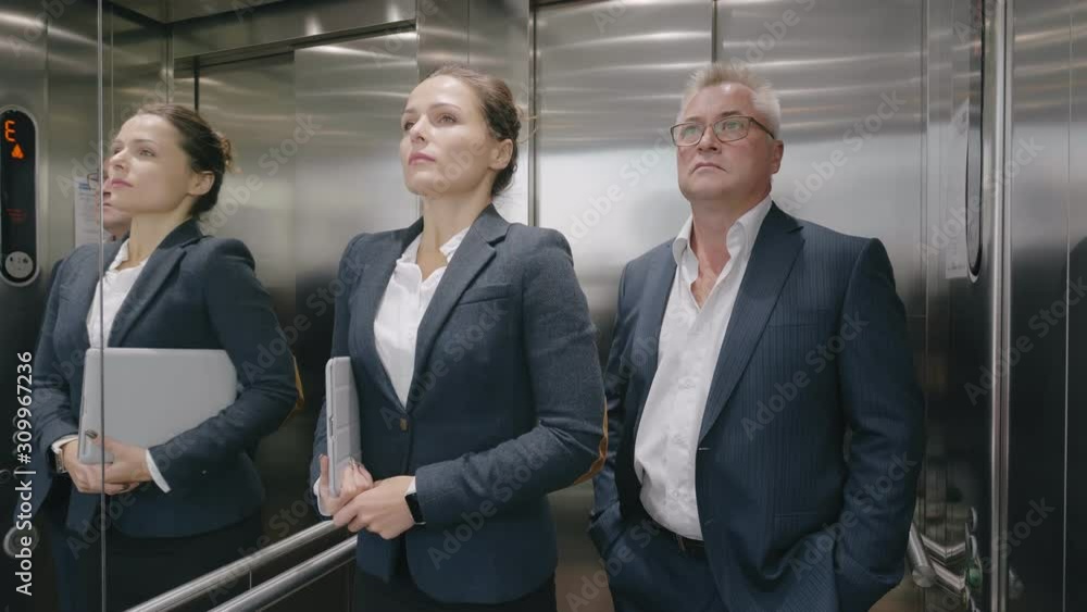 Confient business people exit leave modern metallic elevator, businessman and businesswoman stay calm keep silence during rising to office floor Confient business people exit leave modern metallic elevator, businessman and businesswoman stay calm keep silence during rising to office floor