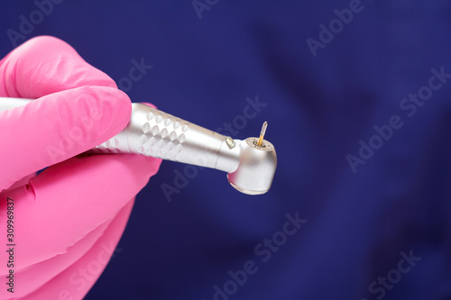 Dentist's hand in glove with dental handpiece.