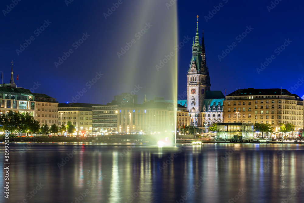 Panoramic view of the Binnenalster lake with fountain and the center of Hamburg at night.