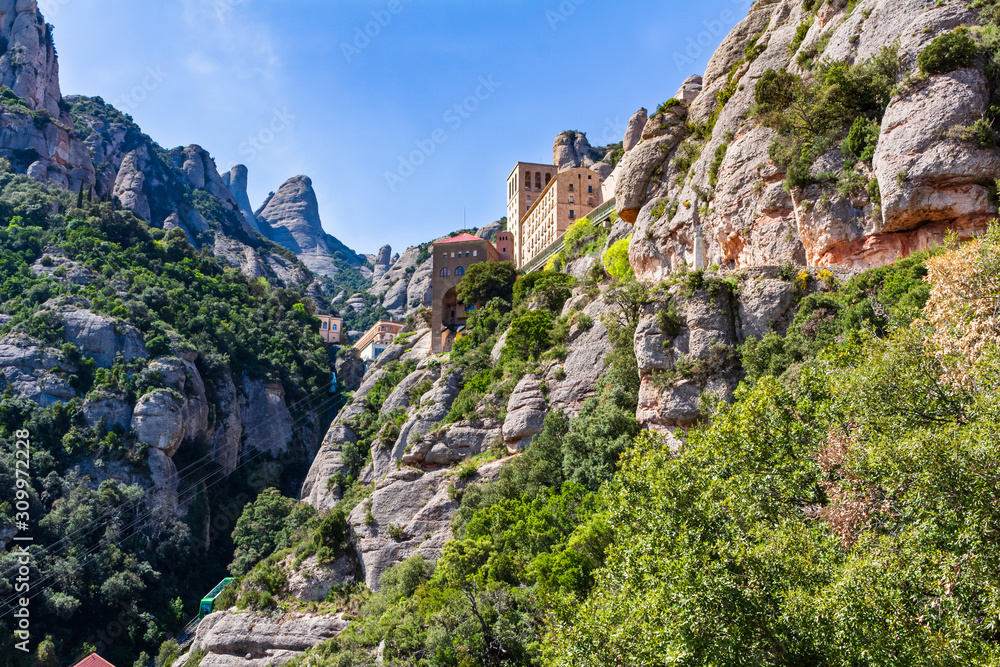View of the tourist-religious complex of Montserrat hanging on a hillside of the mountain massif, Monistrol de Monserrat, Catalonia, Spain