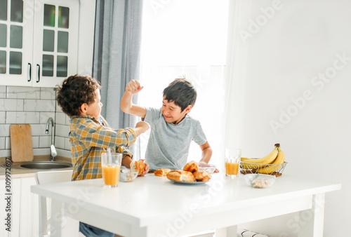 Obraz na płótnie Two siblings tween boys real brothers fight at breakfast table on bright kitchen