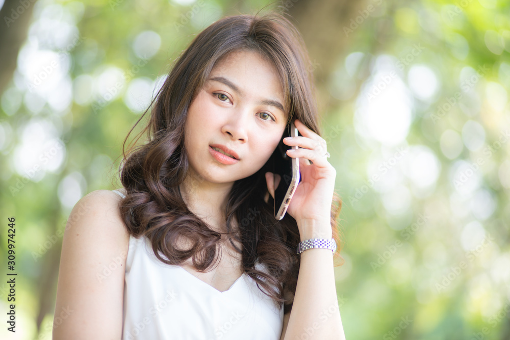 Attractive asian beautiful women sitting on green grass talking smartphone Attractive asian beautiful women sitting on green grass talking smartphone