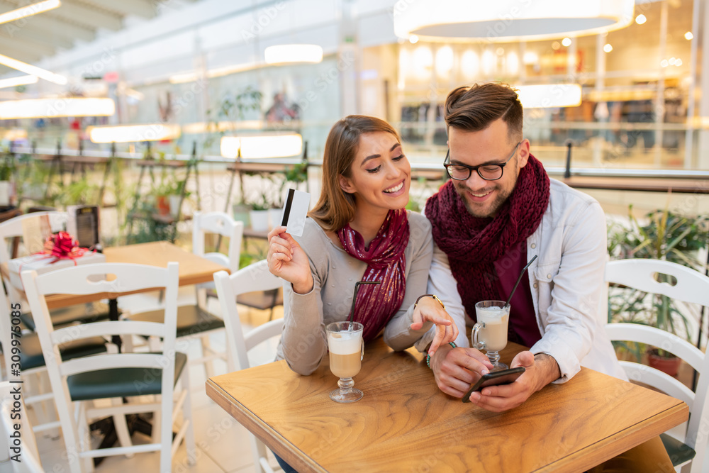 A couple is testing out a new debit card by buying something they like over the phone. They are making a choice at the moment. Cafe interior. A couple is testing out a new debit card by buying something they like over the phone. They are making a choice at the moment. Cafe interior.
