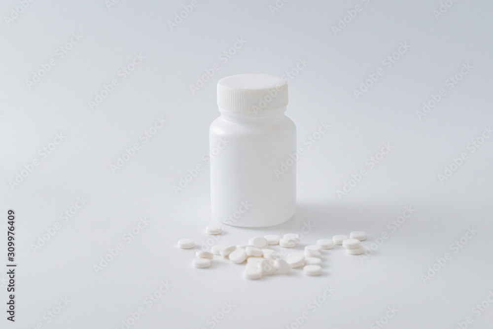 White pills in a white plastic bottle on a light background. Medical pharmacy concept White pills in a white plastic bottle on a light background. Medical pharmacy concept