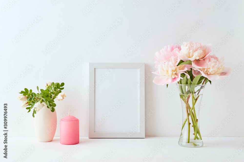 Mockup with a white frame and pink peonies in a vase on a white background Mockup with a white frame and pink peonies in a vase on a white background