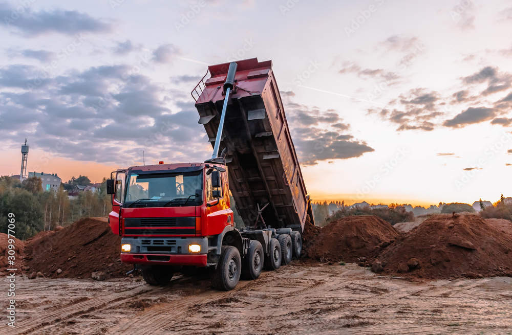 A dump truck is dumping gravel on an excavation site A dump truck is dumping gravel on an excavation site