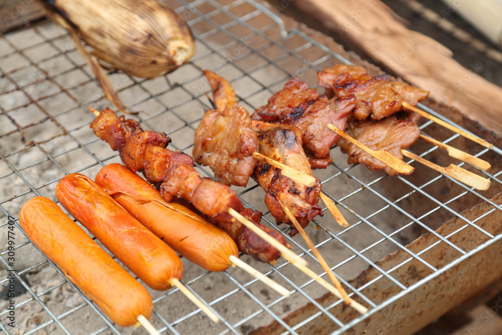 Sausage and belly pork and chicken wing and pork bbq on steel grating street food in Thailand