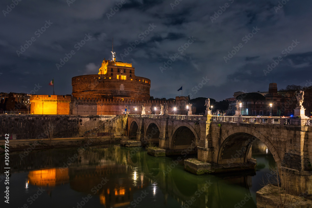 Die historische Engelsburg in Rom mir beleuchteter Brücke über den Tiber im Vordergrund.