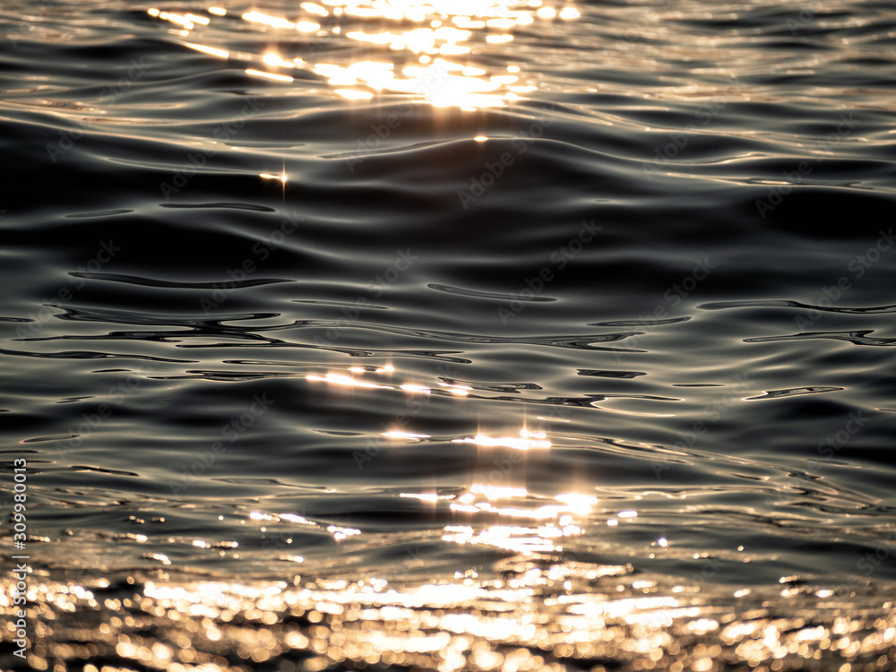 Closeup of water rippled surface with sunshine at sunset evening time Closeup of water rippled surface with sunshine at sunset evening time