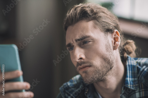 Worried young handsome man looking at his smartphone