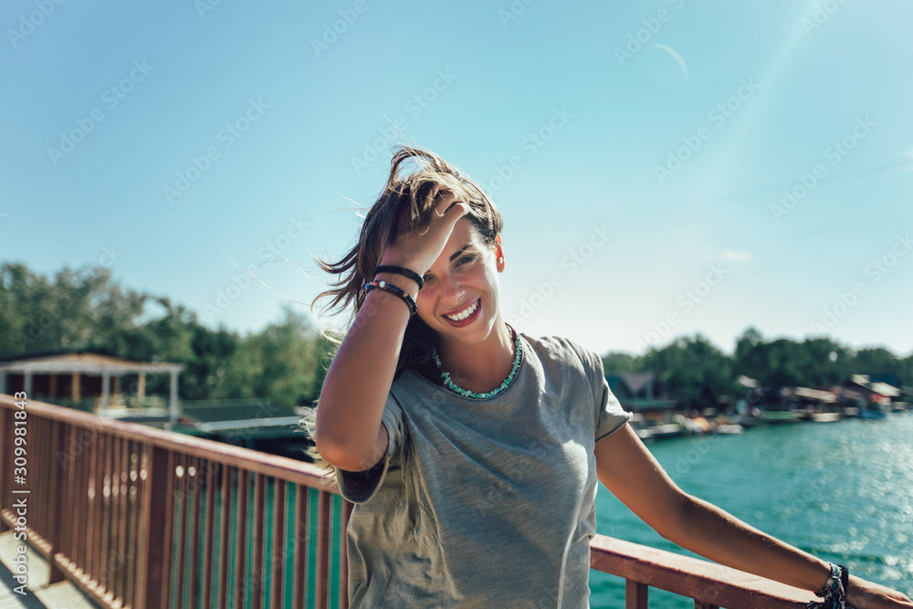 Portrait of happy smiling woman standing on the bridge on sunny summer or spring day outside.