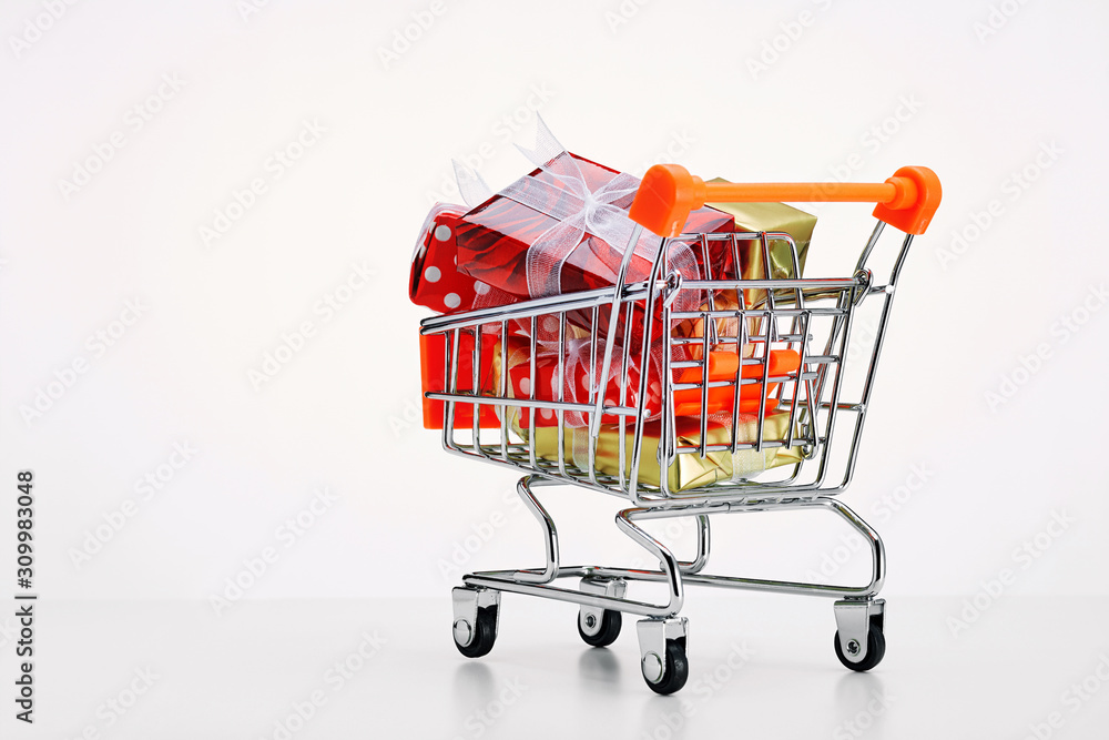 Shopping cart trolley full of colorful gift boxes on white background