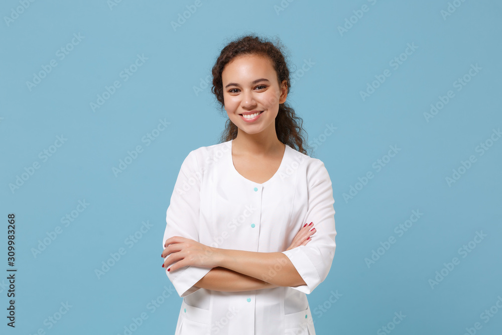 Pretty african american doctor woman isolated on blue background in studio. Female doctor in white medical gown holding hands crossed. Healthcare personnel health medicine concept. Mock up copy space. Pretty african american doctor woman isolated on blue background in studio. Female doctor in white medical gown holding hands crossed. Healthcare personnel health medicine concept. Mock up copy space.