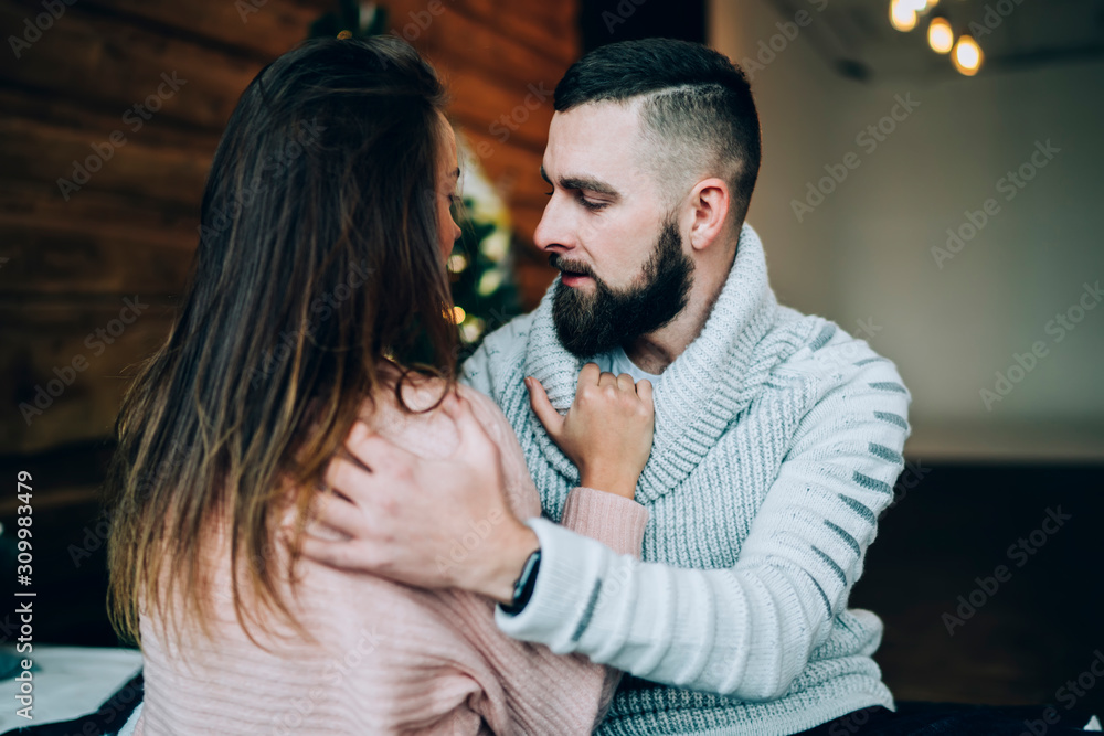 Young couple hugging with lights and Christmas tree on background