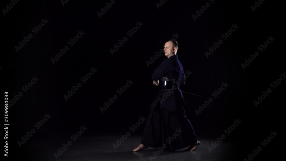 Kendo warrior practicing martial art with the Katana sword on black background. Slow motion Kendo warrior practicing martial art with the Katana sword on black background. Slow motion