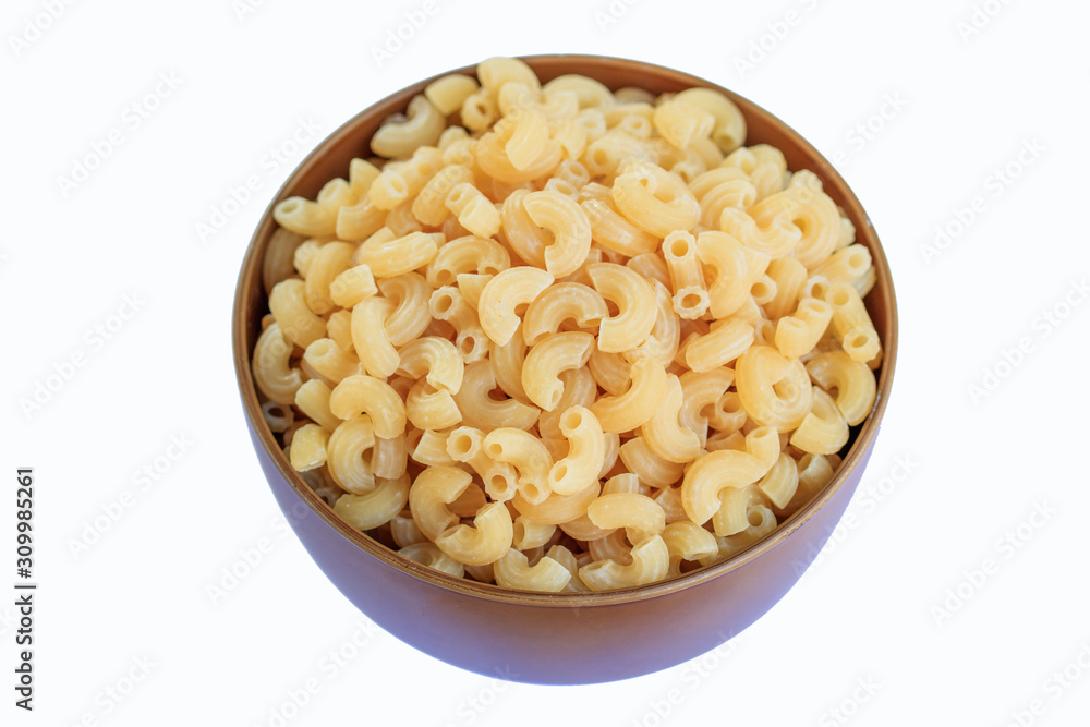 Elbow macaroni in brown bowl on a white background. Elbow macaroni in brown bowl on a white background.