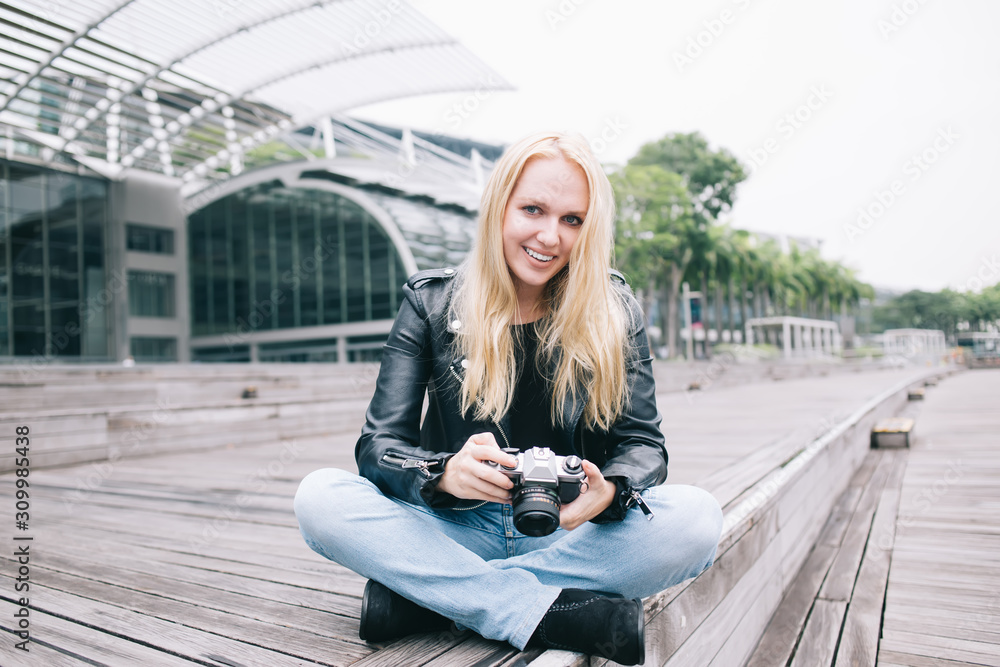 Stylish cheerful photographer with camera on street