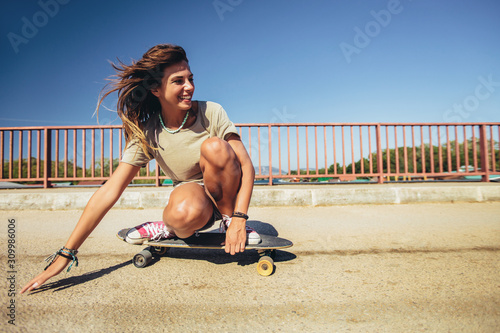 Young sporty woman riding on the skateboard on the road. photo