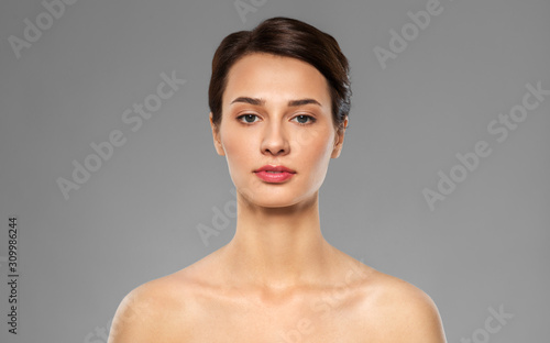 beauty, bodycare and people concept - beautiful young woman with bare shoulder over grey background