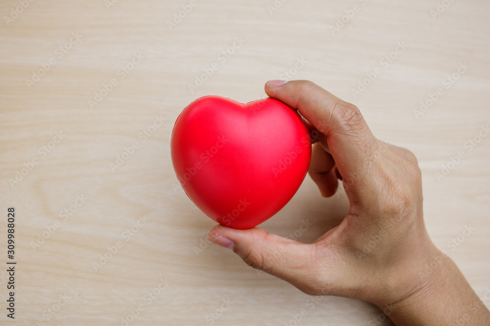 Red heart on hand on wooden background. Red heart on hand on wooden background.