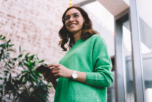 Cheerful young woman standing with smartphone