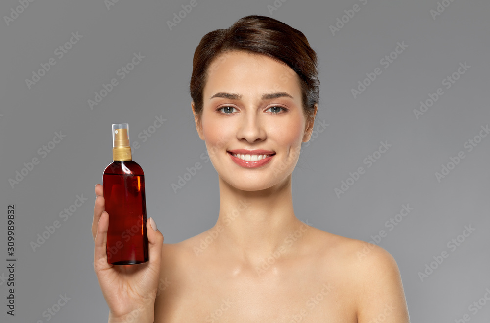 beauty, bodycare and people concept - beautiful young woman with sun protective oil over grey background beauty, bodycare and people concept - beautiful young woman with sun protective oil over grey background
