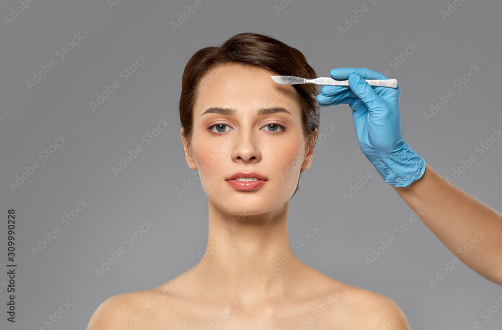 plastic surgery and beauty concept - beautiful young woman and hand with scalpel over grey background and snow