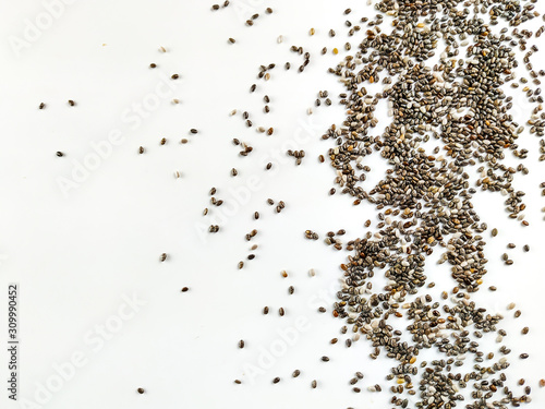 Delicious and healthy superfood chia seed randomly placed on white background on right side of the image forming an interesting frame of healthy food © Emir