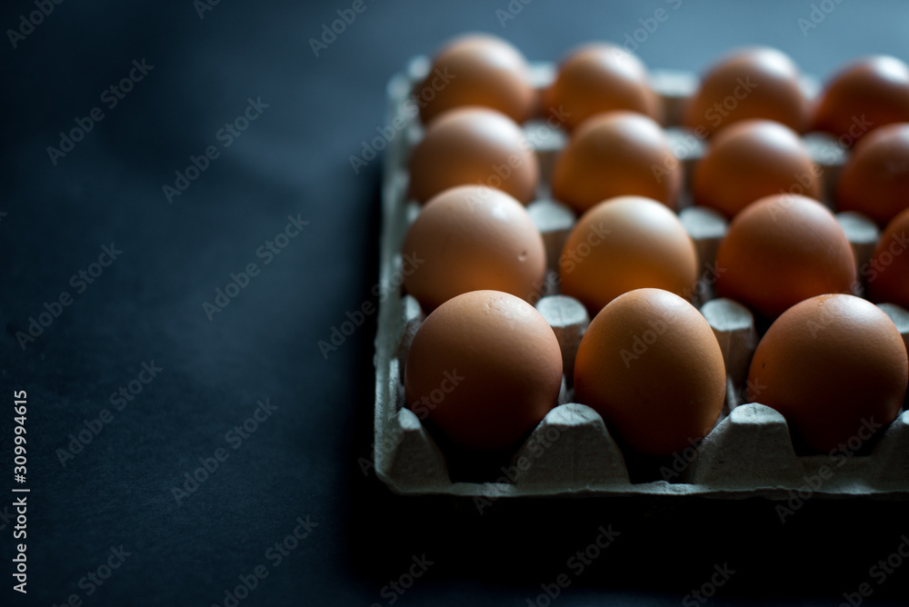 A dozen eggs in a cardboard open package on a black background top view. Fresh broken quail eggs lies in a cardboard box (a beautiful yellow yolks in the shell). Copy space. Abstract concept A dozen eggs in a cardboard open package on a black background top view. Fresh broken quail eggs lies in a cardboard box (a beautiful yellow yolks in the shell). Copy space. Abstract concept