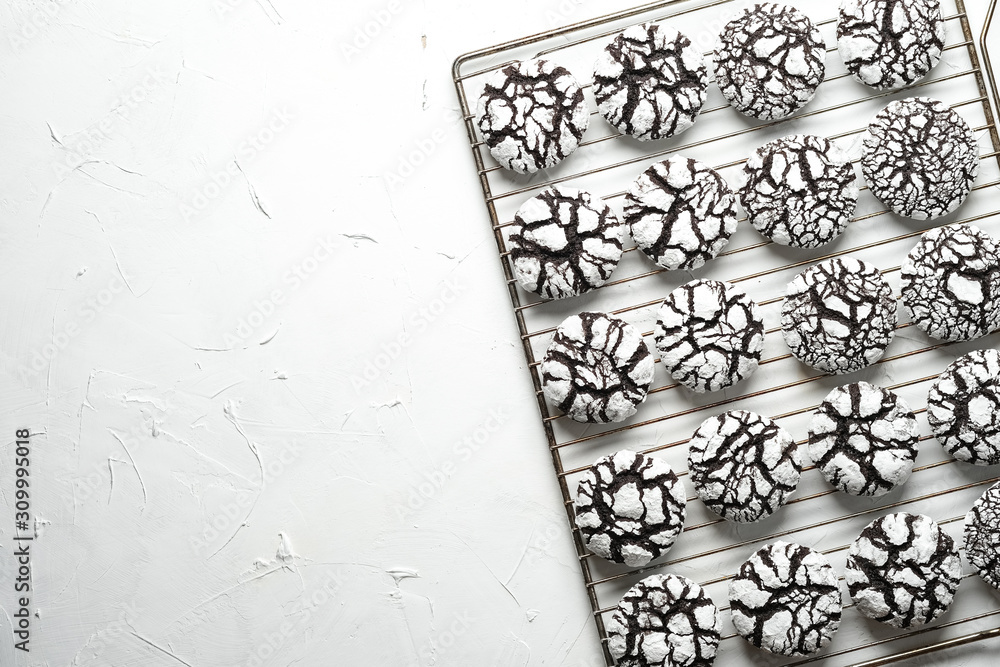 Chocolate crinkle cookies with powdered sugar icing. Cracked chocolate biscuits on an iron lattice on a light background top view copy space