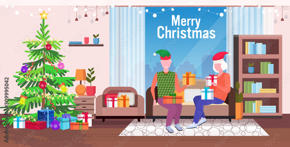 senior man in elf hat giving present gift box to mature woman family sitting on couch celebrating merry christmas happy new year winter holidays concept modern living room interior full length