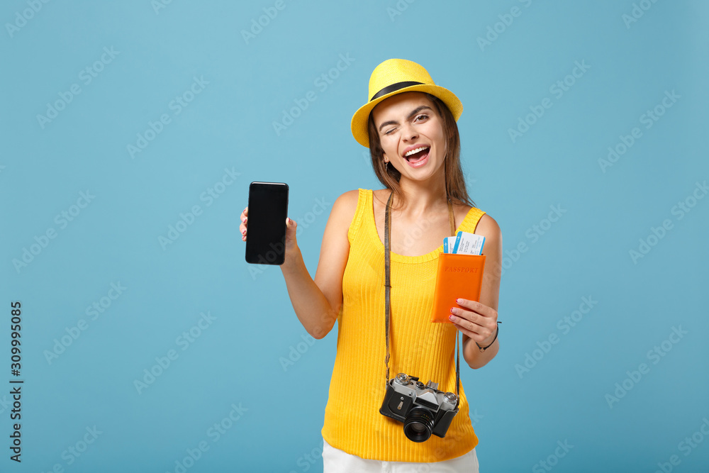Traveler tourist woman in yellow casual clothes hat hold tickets cellphone camera isolated on blue background. Female passenger traveling abroad travel on weekends getaway. Air flight journey concept.