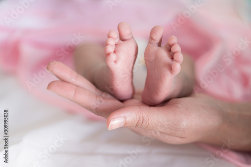 Baby foots on mother hand.Newborn baby feet and relax action with pink blanket.Happy time family concept. © arcyto
