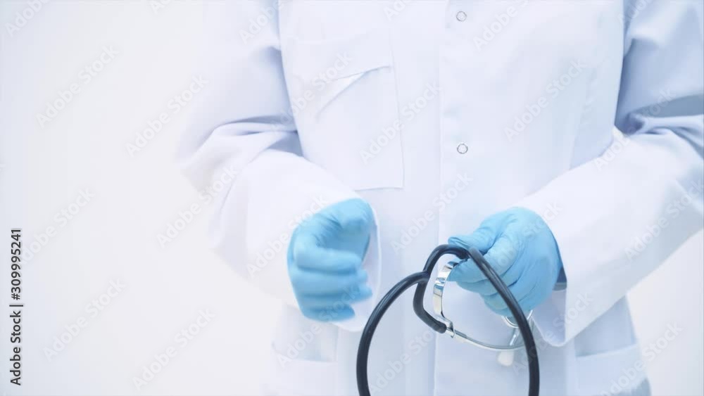 Cropped shot of doctor in white coat and blue disposable gloves holding a stethoscope. Cropped shot of doctor in white coat and blue disposable gloves holding a stethoscope.