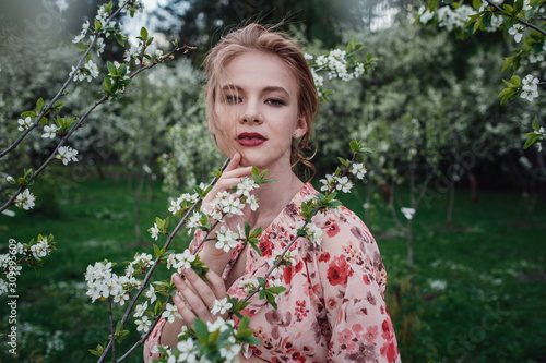 Young beautiful woman in the cherry-blossoming garden.
